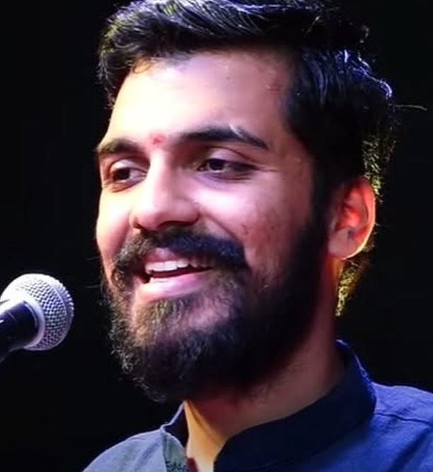 A singer smiling beside a microphone